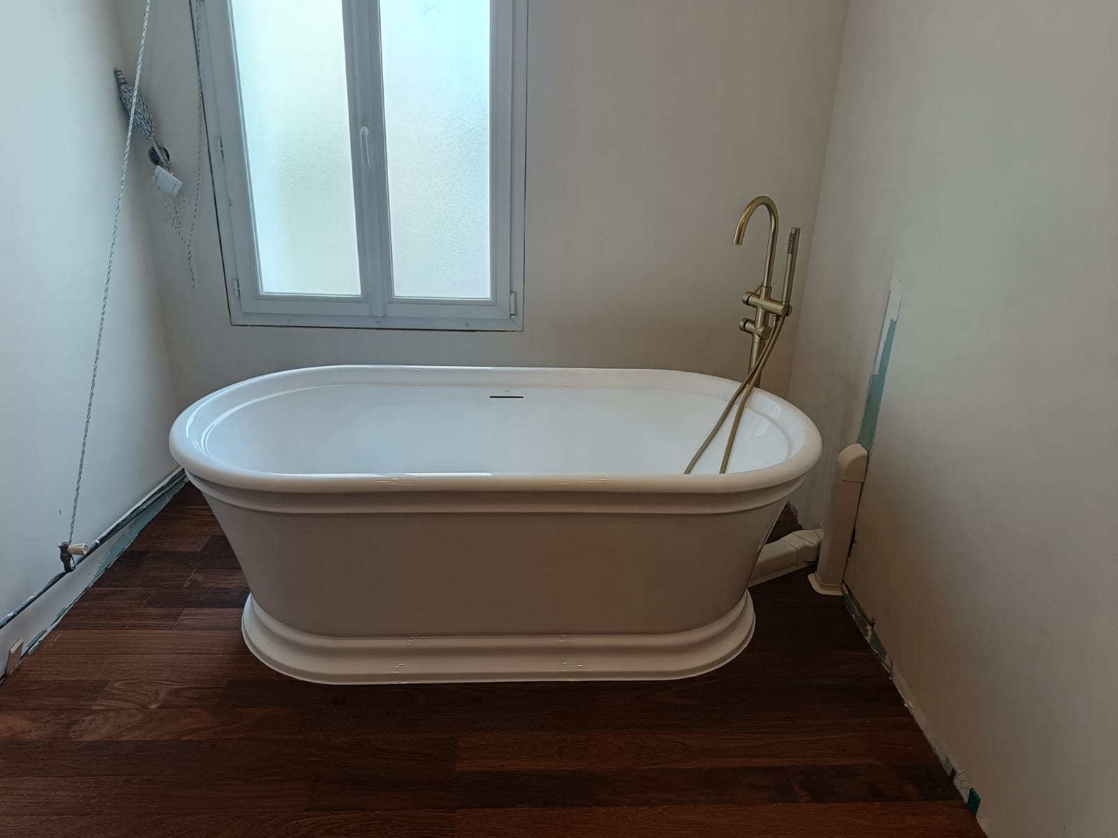 Pose d'une baignoire îlot avec robinetterie dorée